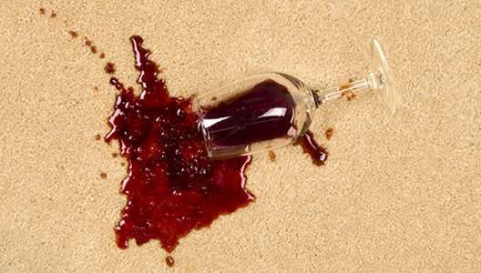 This image shows a wine glass that fell on a carpet spilling the wine.