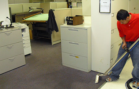 This image shows a man cleaning a carpet in the office.