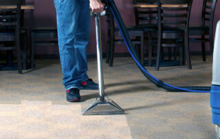 This image shows a man cleaning a dirty carpet in a restaurant.