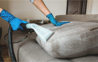 This image shows a sofa that is being cleaned with a vacuum machine.