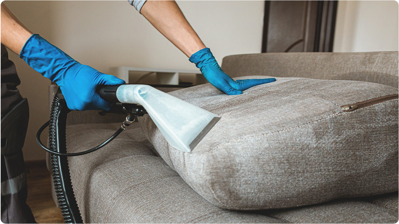This image shows a sofa that is being cleaned with a vacuum machine.