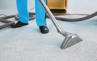 This image shows a vacuum machine being used to clean a carpet in an office.