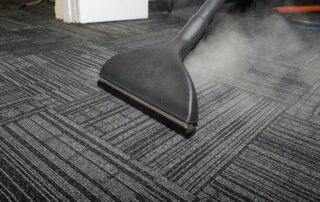 This image shows a steam cleaning machine being used to clean a carpet.